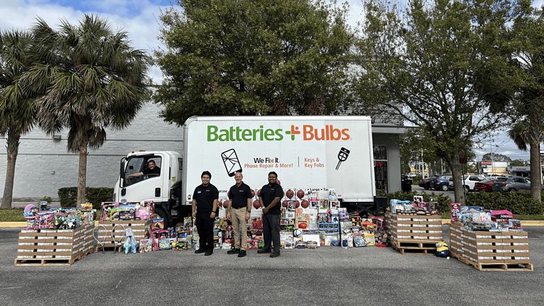 Image of Batteries Plus team members with Truck donating batteries and toys to Toys For Tots