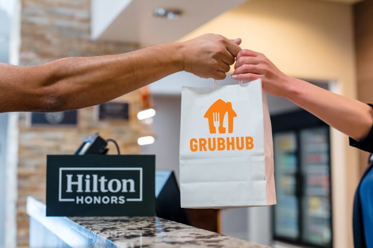 Image of person handing grubhub bag over counter to hilton team member