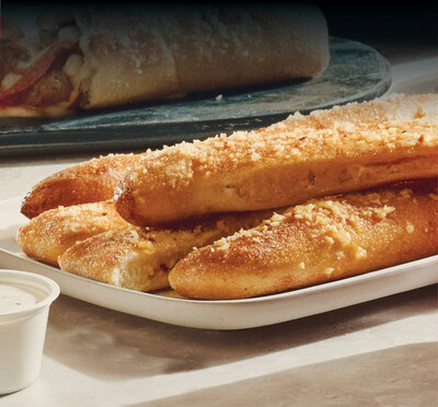 Image of New Bread Sticks on Menu at Marco's Pizza. 4 sticks on bottom with one on top; located near dipping sauce. 