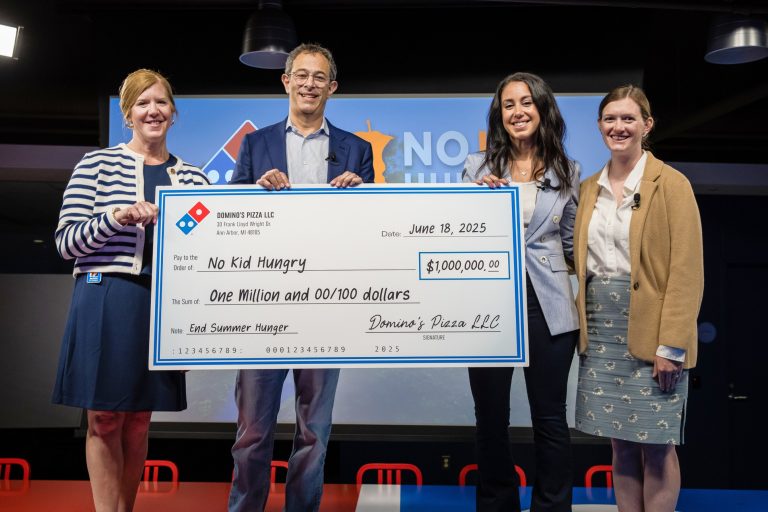 Three people holding a check for a charity event.