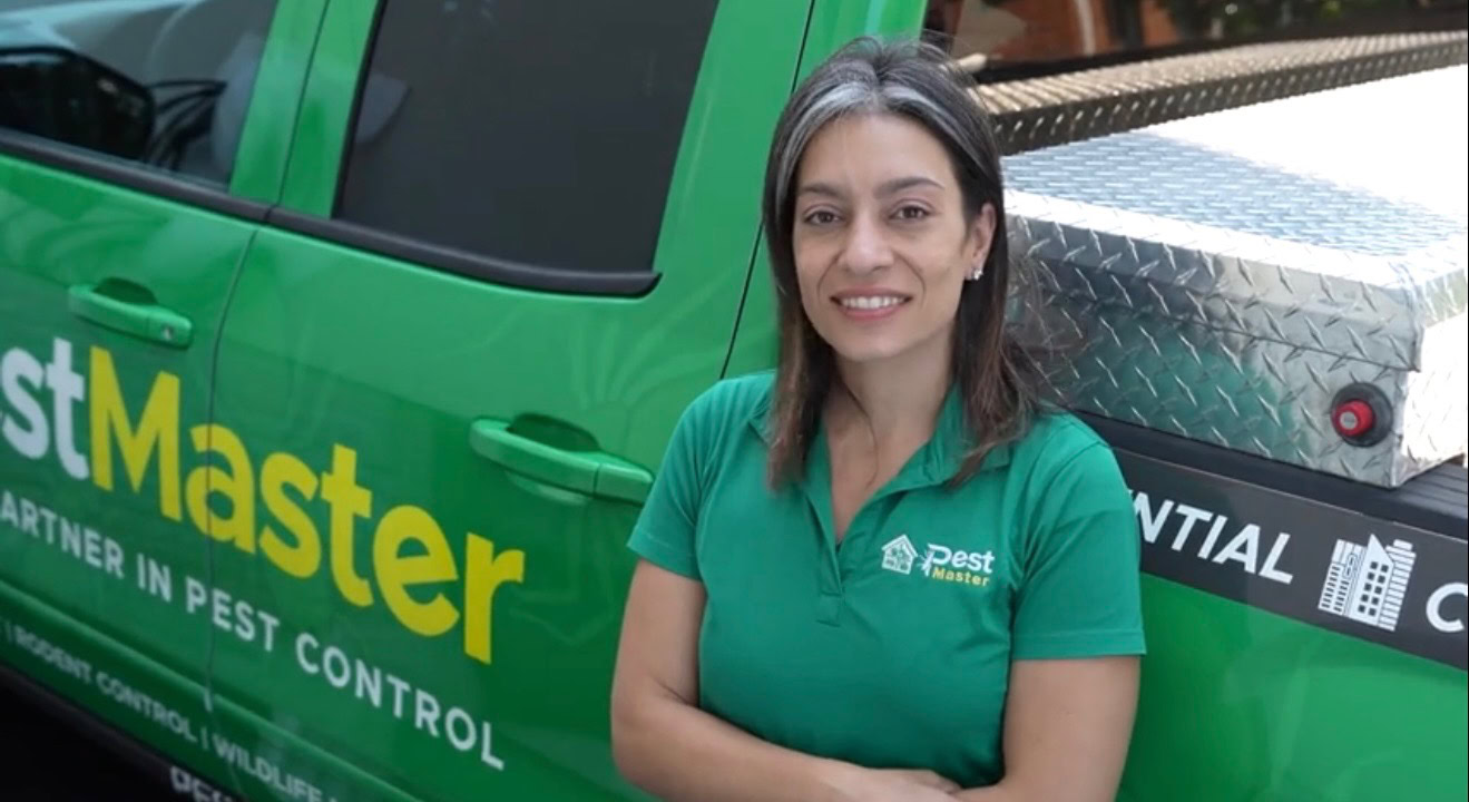 A woman in green shirt standing next to a green truck.